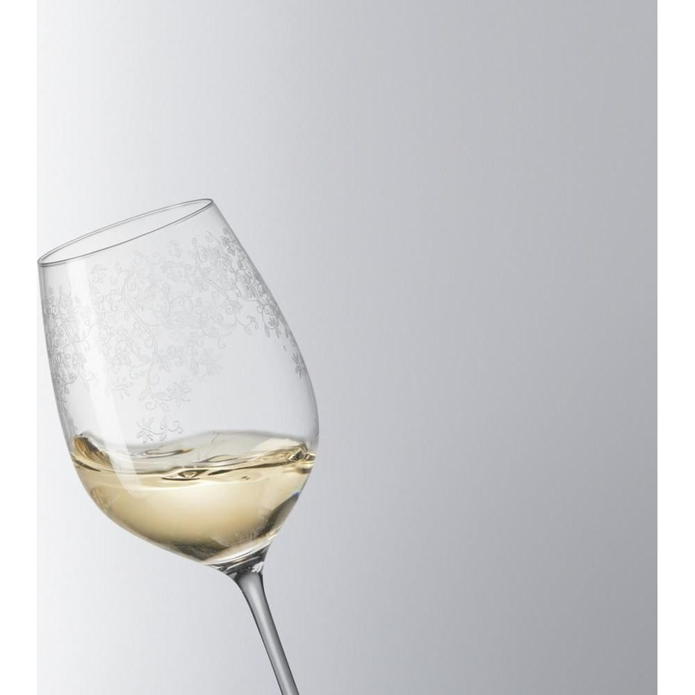 Ein Weinglas mit weißem Wein, verziert mit floralen Mustern.