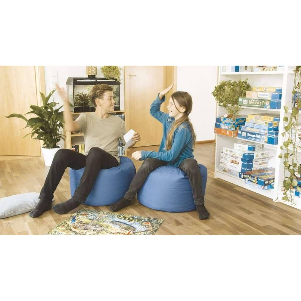 Dwoje dzieci siedzi na niebieskich workach sako i daje sobie piątkę.