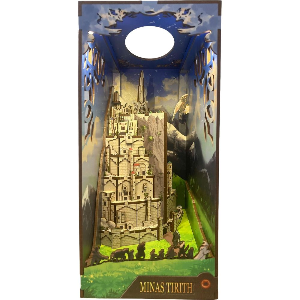 Diorama Minas Tirith z miastem, górą i postaciami na zielonej trawie.