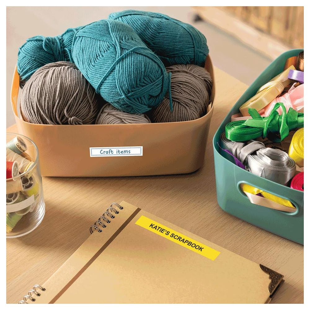 Dwa pojemniki z materiałami do rękodzieła, jak wełna, wstążki i szpulki.