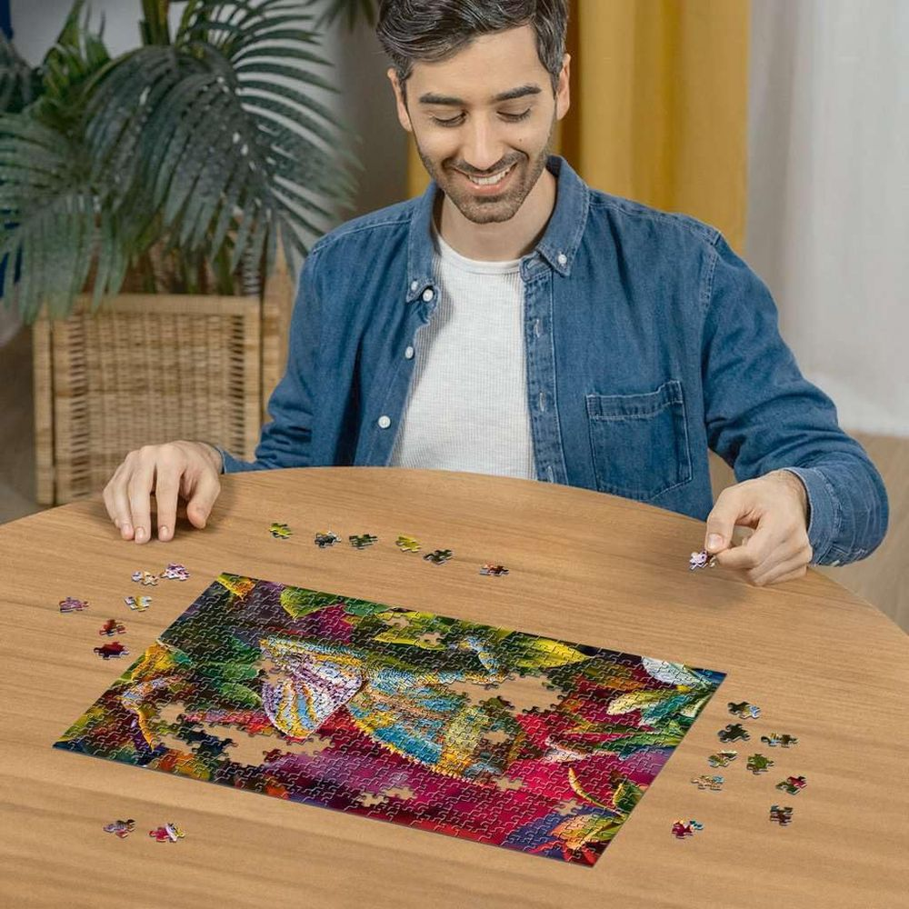 Homme assemblant un puzzle de caméléon sur une table en bois.