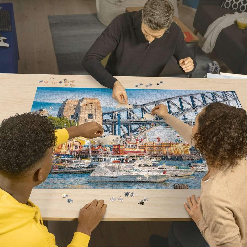 Trois personnes assemblent un puzzle de Sydney Harbour Bridge et de bateaux.