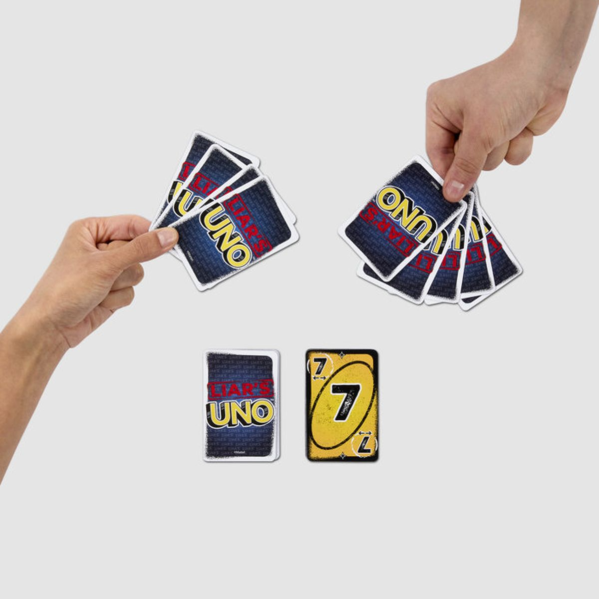 Due mani tengono carte Uno, con una carta numero 7 sul tavolo.