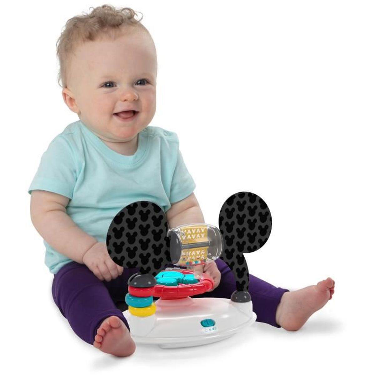 Un bebé se sienta y juega con un juguete colorido con orejas de Mickey Mouse.