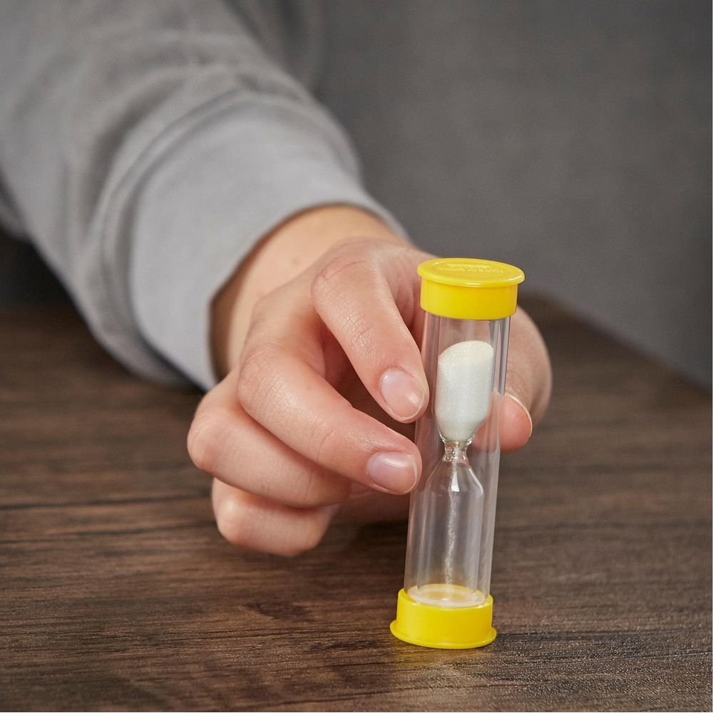 Een hand houdt een kleine zandloper vast met gele dopjes en wit zand.