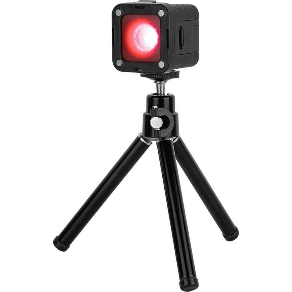 A black, square light with a red glow on a small black tripod.
