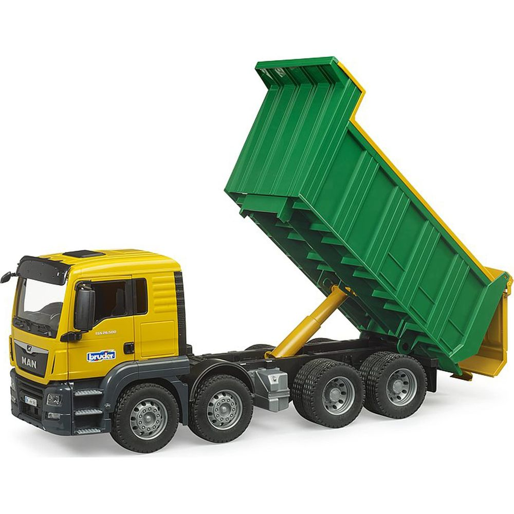 Un camion dumper MAN giallo con il suo container verde sollevato e pistone idraulico esteso.