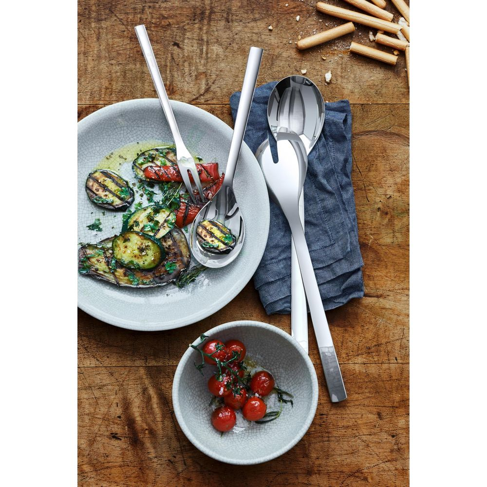 Gegrilltes Gemüse und Kirschtomaten mit Salatbesteck auf Holztisch.