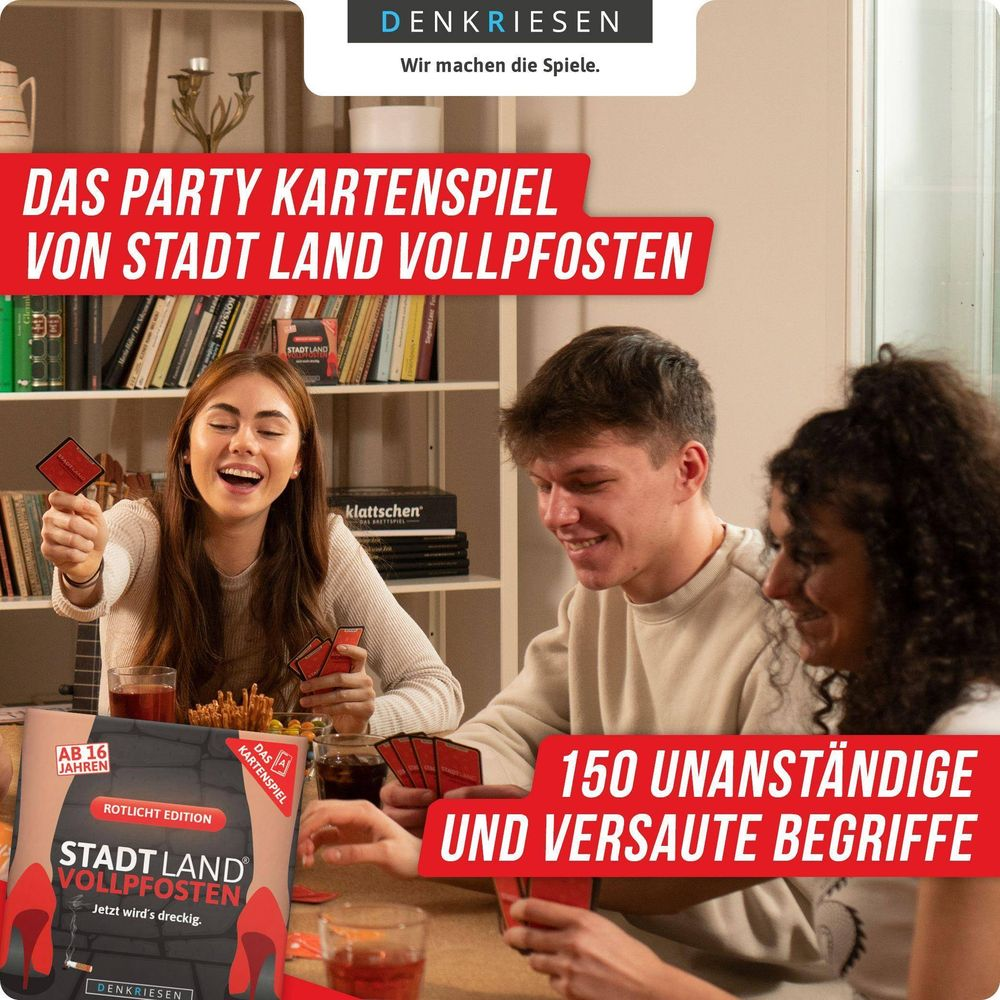 Drei junge Leute spielen ein Kartenspiel, das auf einem Tisch liegt. Die Box ist links.