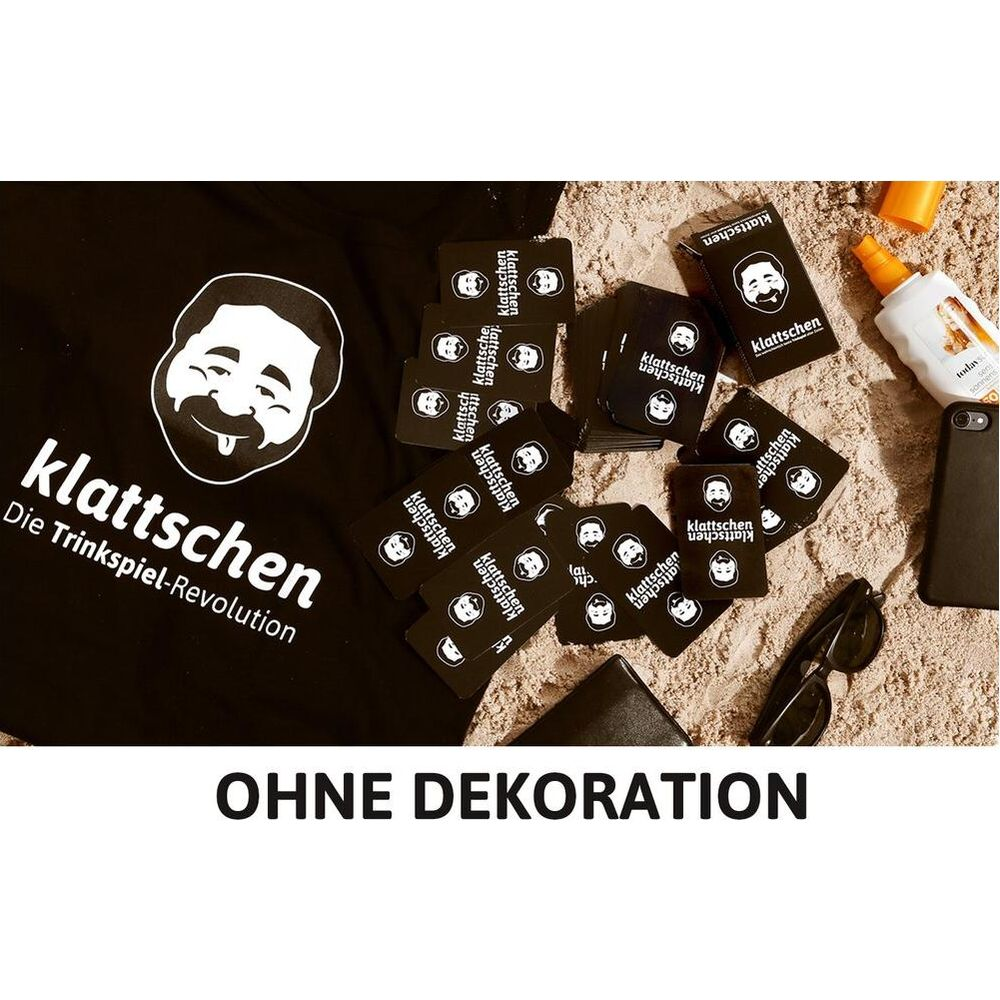 Un t-shirt noir avec logo 'klattschen' sur le sable, avec des cartes de jeu éparpillées.