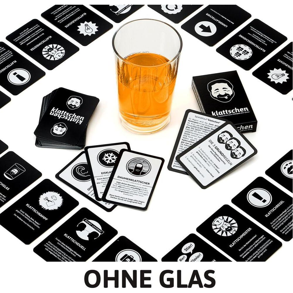 Cartes de jeu, un verre de boisson orange et un plateau de jeu sur une table.