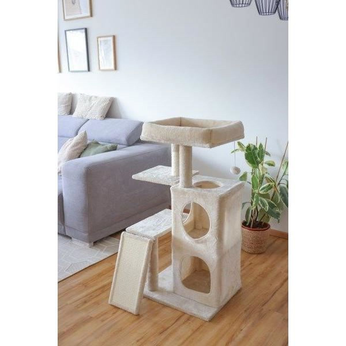 Un árbol rascador beige de varios niveles junto a un sofá gris.
