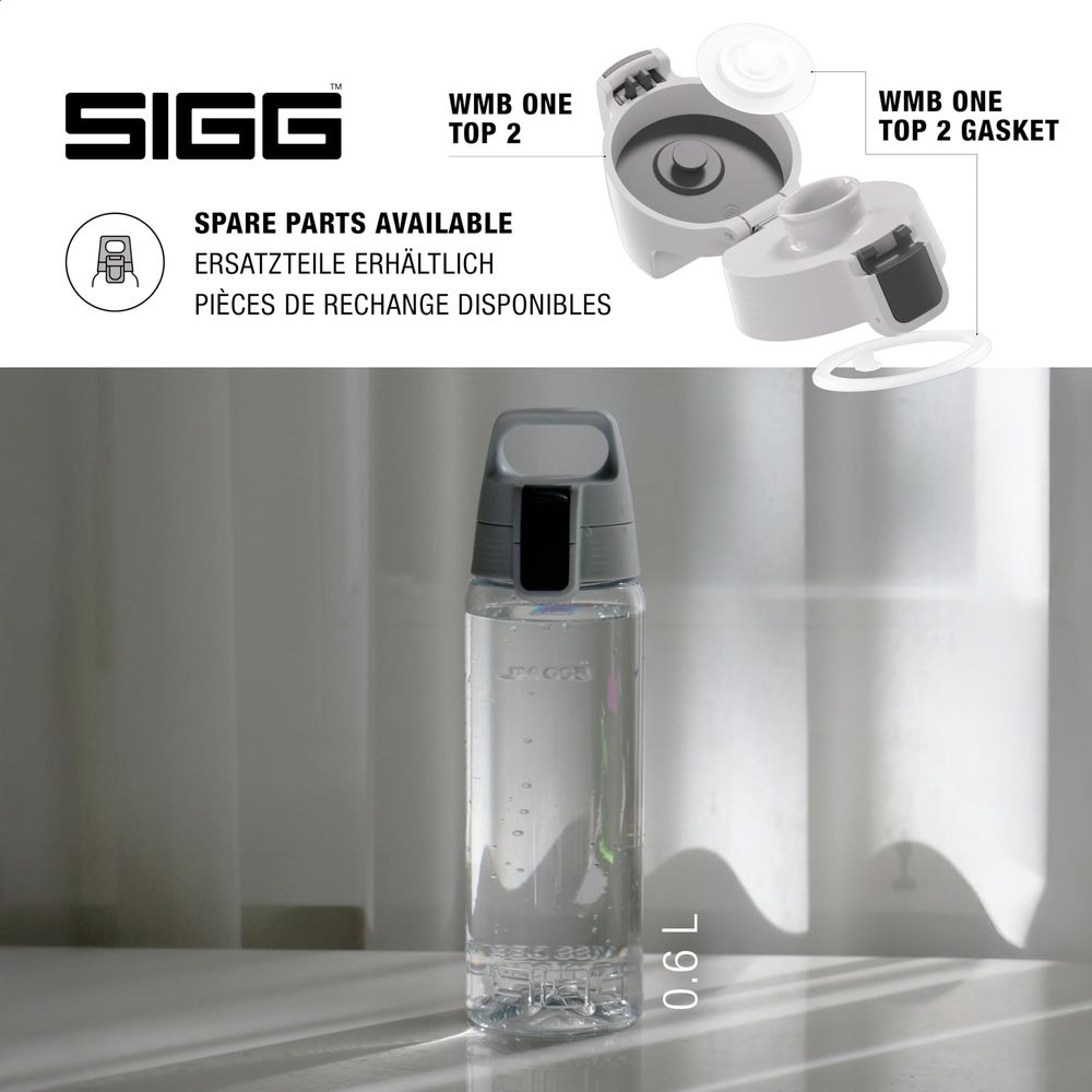 Eine durchsichtige Siggs-Wasserflasche mit grauem Deckel steht vor einem Vorhang.
