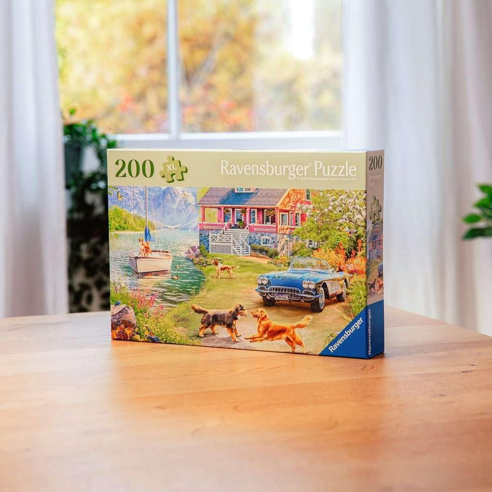 Scatola puzzle con casa, barca, auto e cani vicino al lago con sfondo fogliame autunnale.