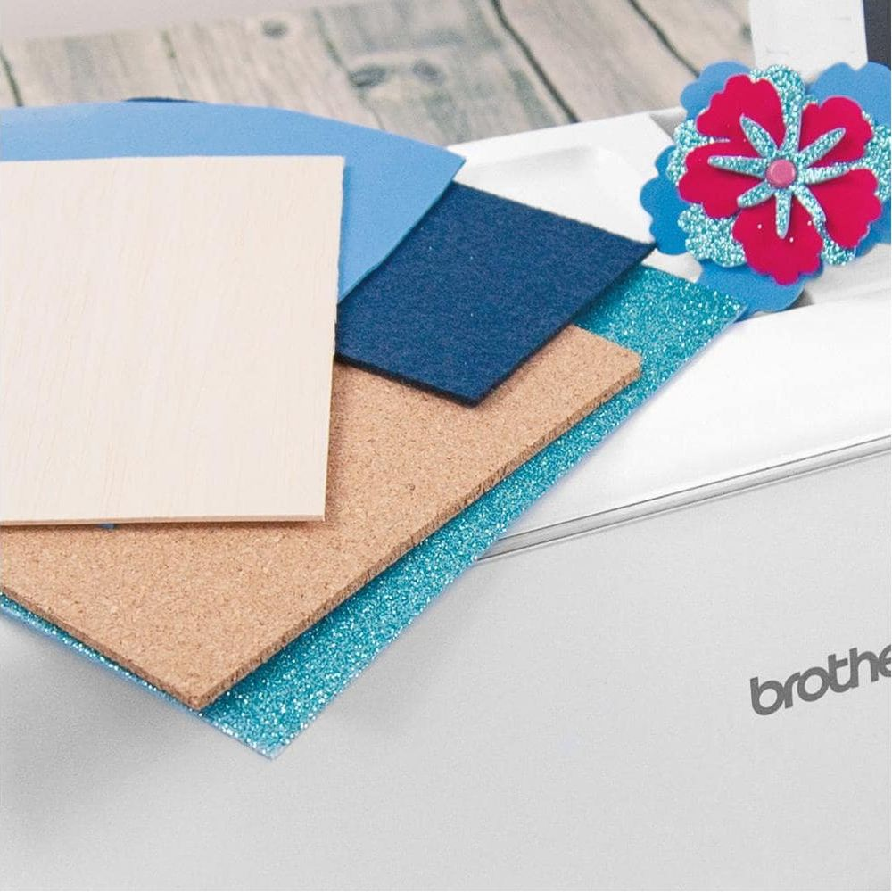 Holz-, Kork- und blaue Glitzerbögen auf einer weißen Schneidemaschine.