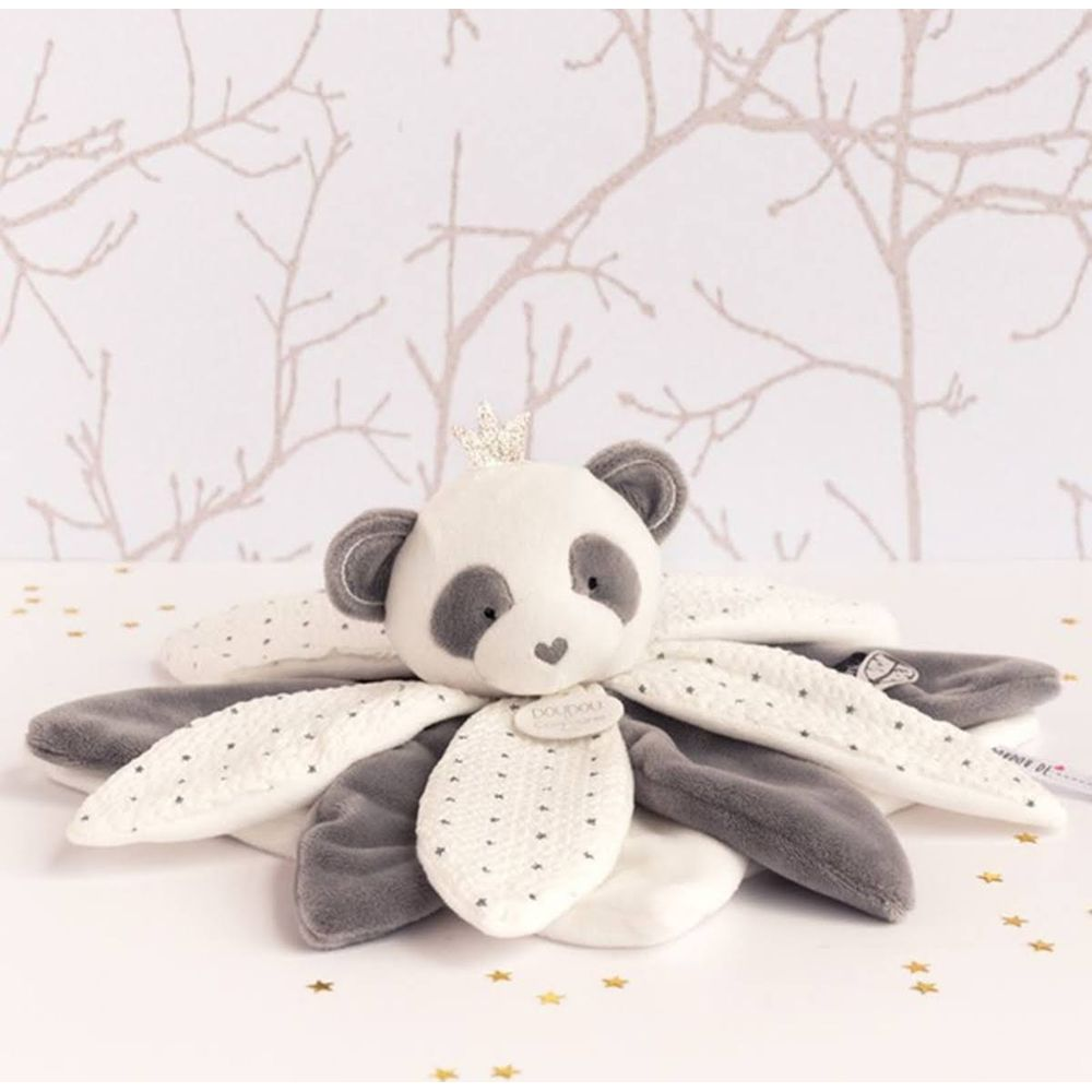 Pluszowa panda z koroną leży na kocyku w gwiazdki.