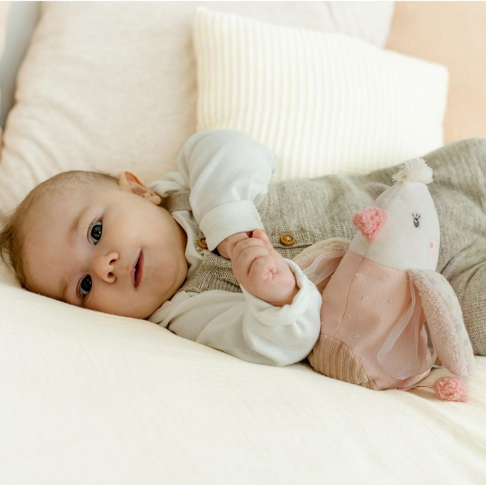 Un bambino è sdraiato sulla schiena accanto a un peluche.