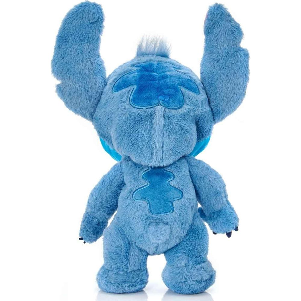 Niebieska pluszowa zabawka Stitch stoi z podniesionymi ramionami na białym tle.