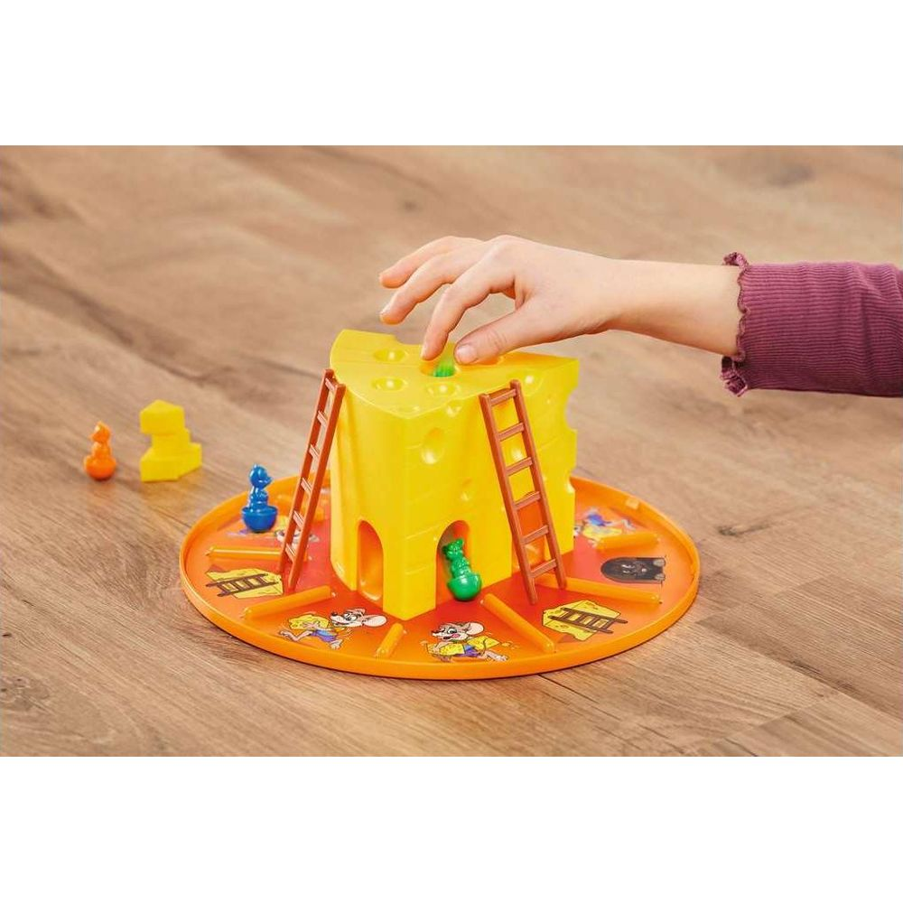 La mano de un niño juega con un juego amarillo con forma de queso con ratones y escaleras.