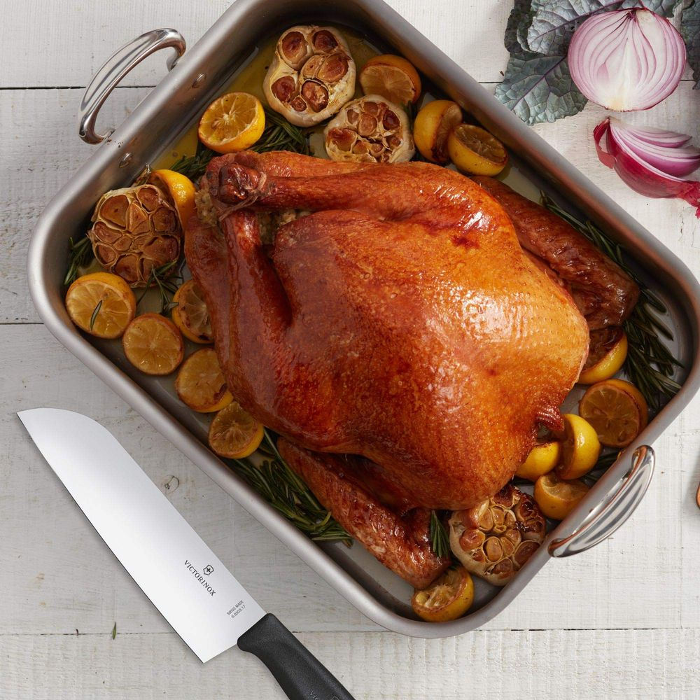 Un pavo asado con limones, ajo y romero en una sartén para asar.