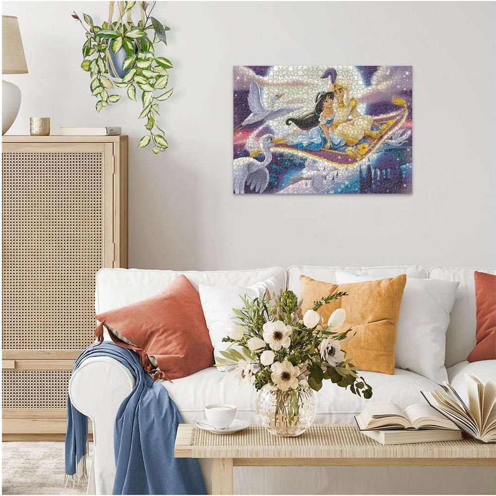 Jasmine i Aladyn lecą na magicznym dywanie nad łabędziami i miastem.