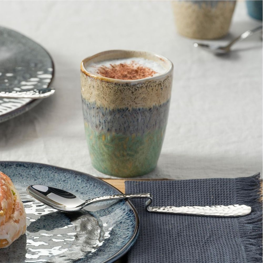 Una tazza di caffè colorata con schiuma e cannella su un tavolo.
