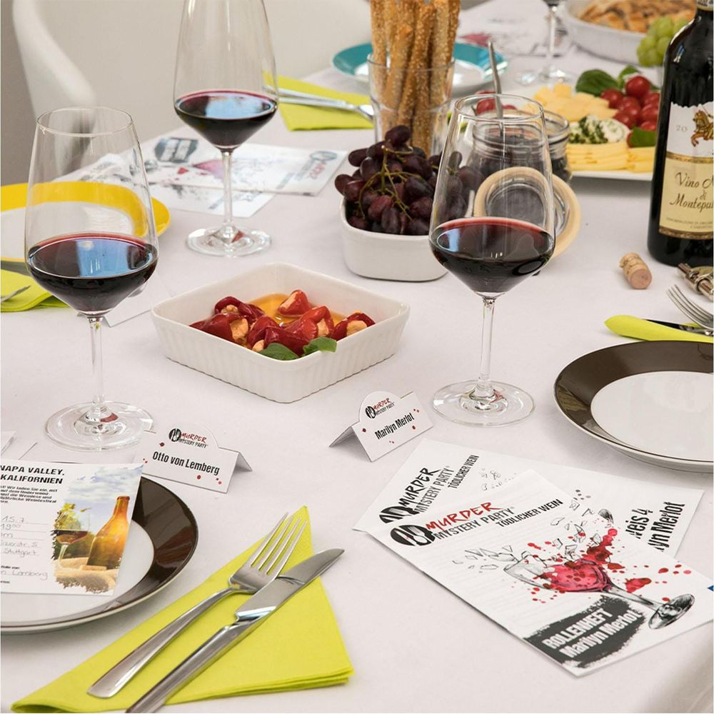 Una tavola apparecchiata per una festa con bicchieri di vino, cibo e carte del gioco.