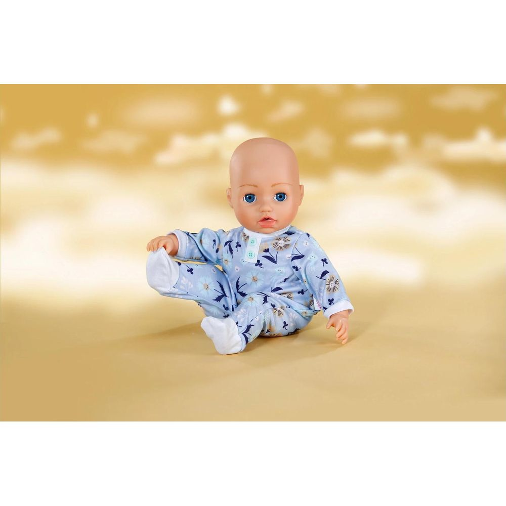Lalka-niemowlę siedzi w niebieskim piżamce w kwiaty. Niebieskie oczy.