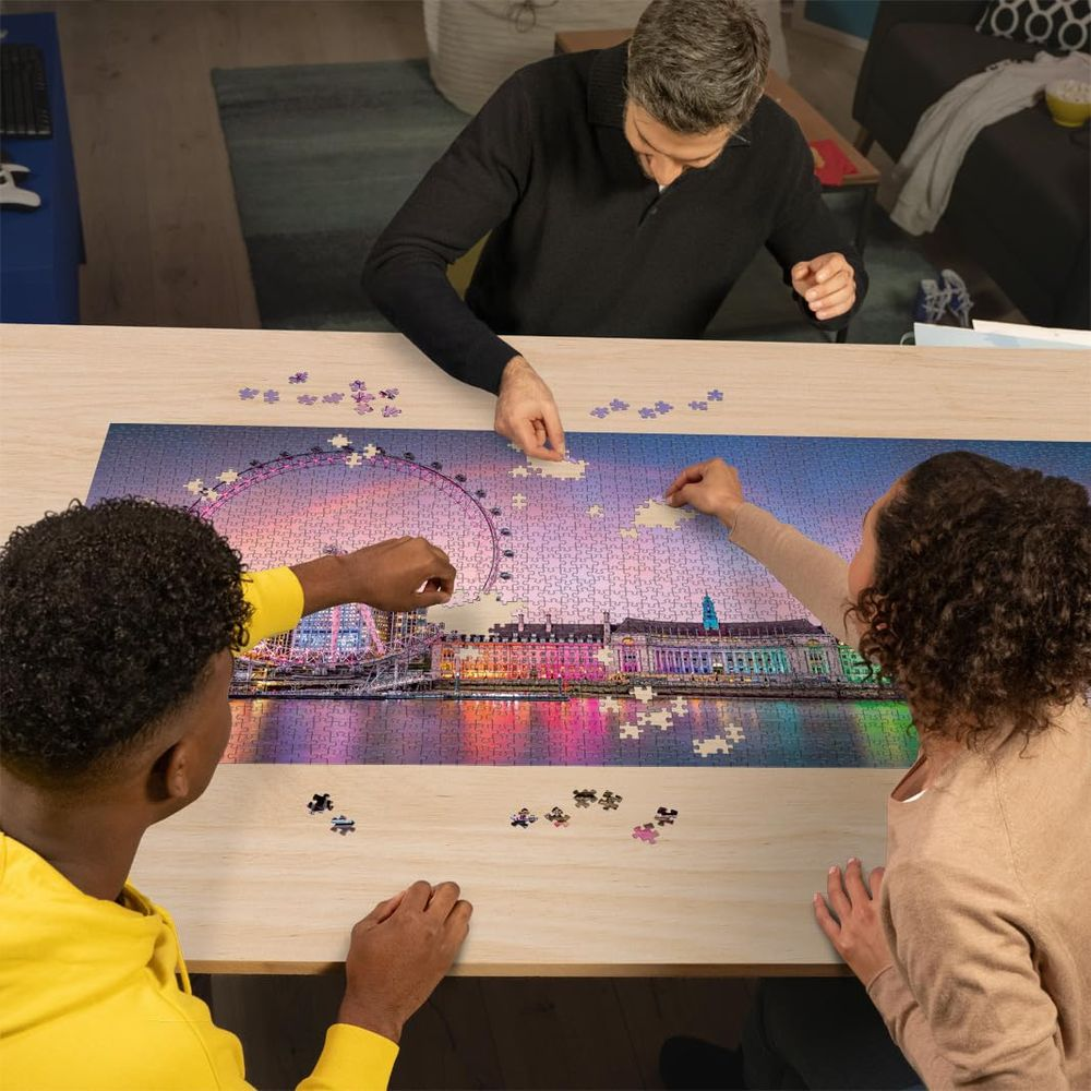 Trois personnes assemblent un puzzle de Londres la nuit avec le London Eye.