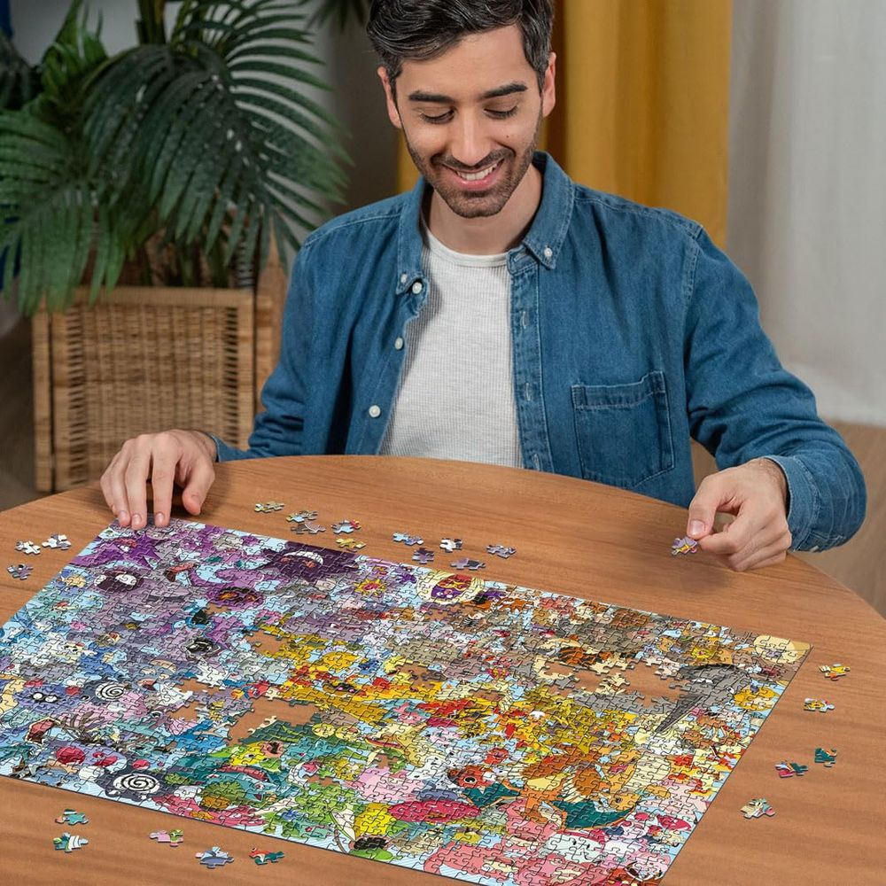 Uomo a un tavolo che assembla un puzzle colorato. Molti piccoli pezzi sparsi.