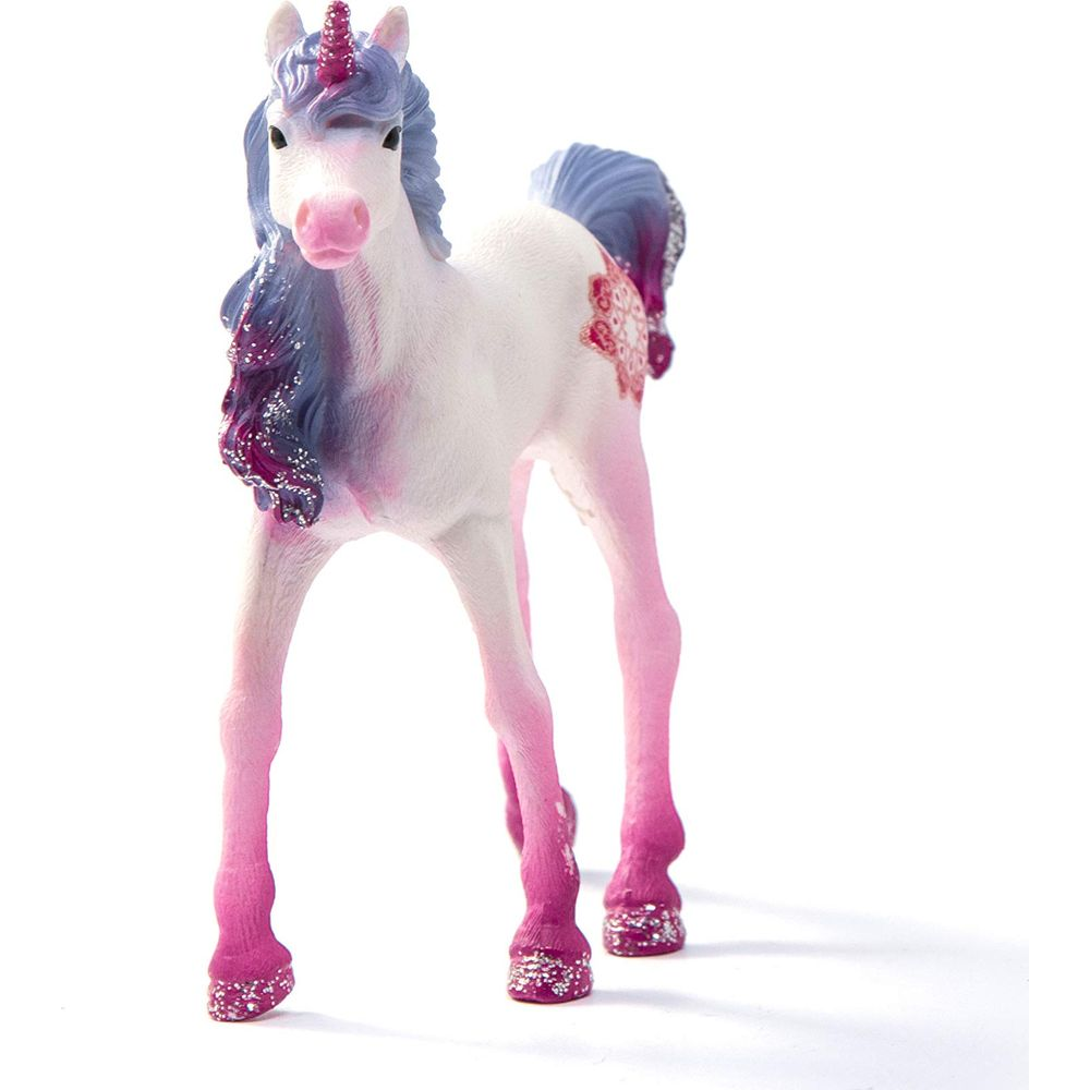 Biała zabawka jednorożca z różowymi i niebieskimi akcentami i brokatem.
