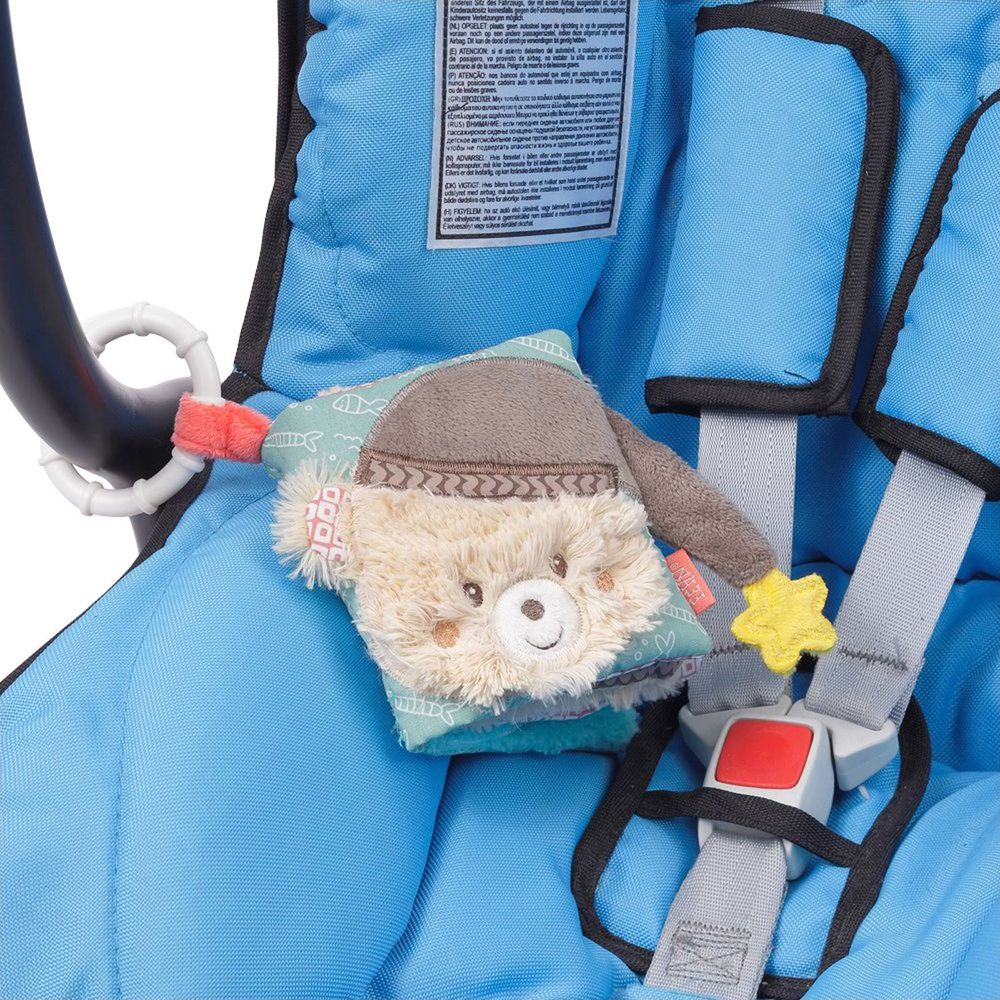 Pluszowa zabawka misia jest przymocowana do niebieskiego fotelika samochodowego.