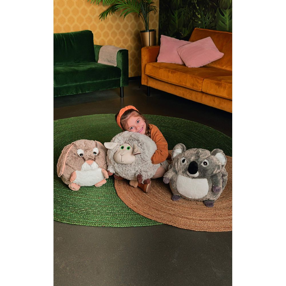 Ein Mädchen sitzt mit drei Plüschtieren (Hase, Schaf, Koala) auf einem Teppich.