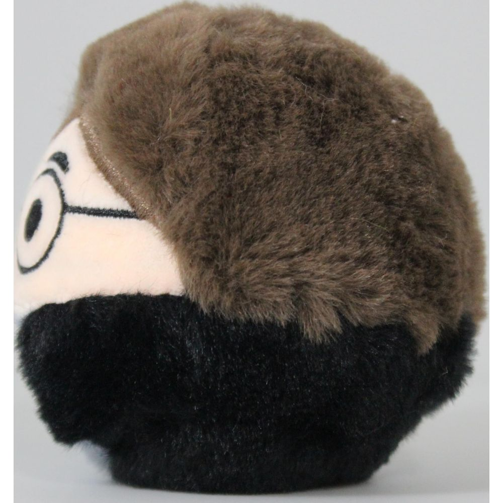 Eine braune Plüschfigur mit schwarzen Haaren und einem Gesicht mit Brille.
