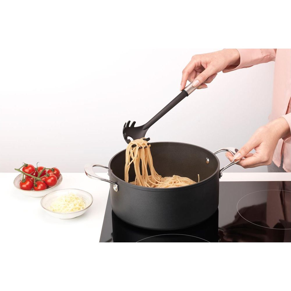 Una persona solleva spaghetti da una pentola con un mestolo per pasta.