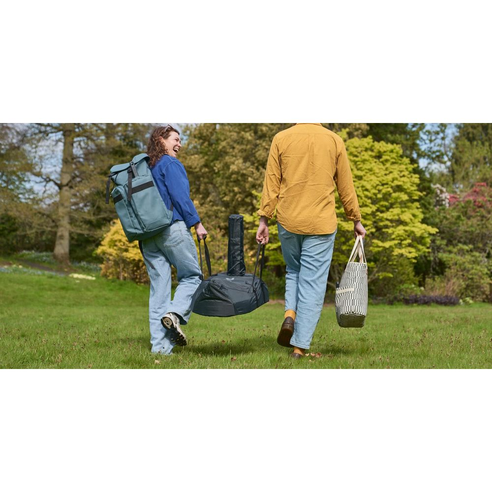 Due persone portano borse in un parco. Donna con zaino a sinistra, persona con borsa tote a destra.