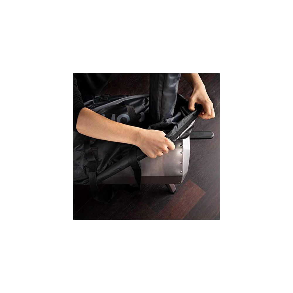 Mani che chiudono una borsa nera con cerniera su una base argentata, su pavimento in legno.