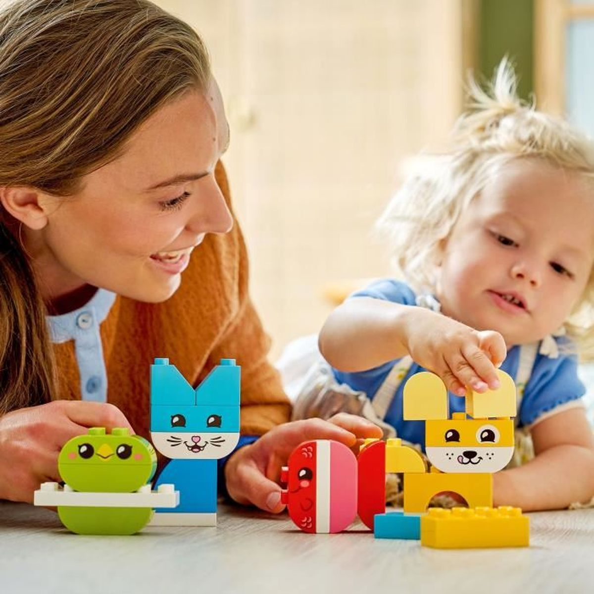 Bir kadın ve bir çocuk renkli Duplo bloklarla oynuyor.