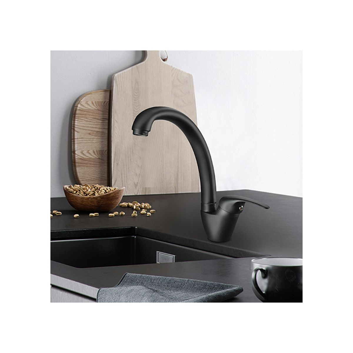 Rubinetto nero sopra un lavello con taglieri di legno e una ciotola di noci.