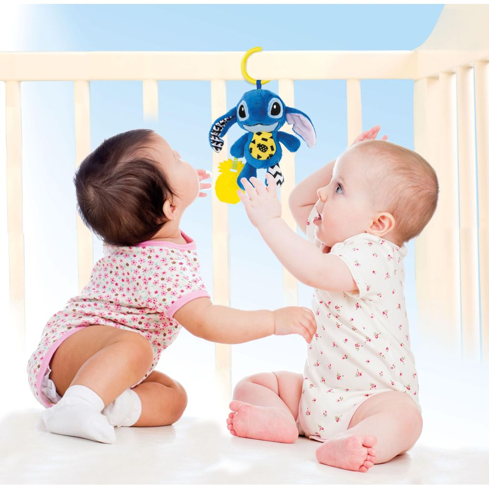 Due neonati giocano con un peluche blu sopra di loro.