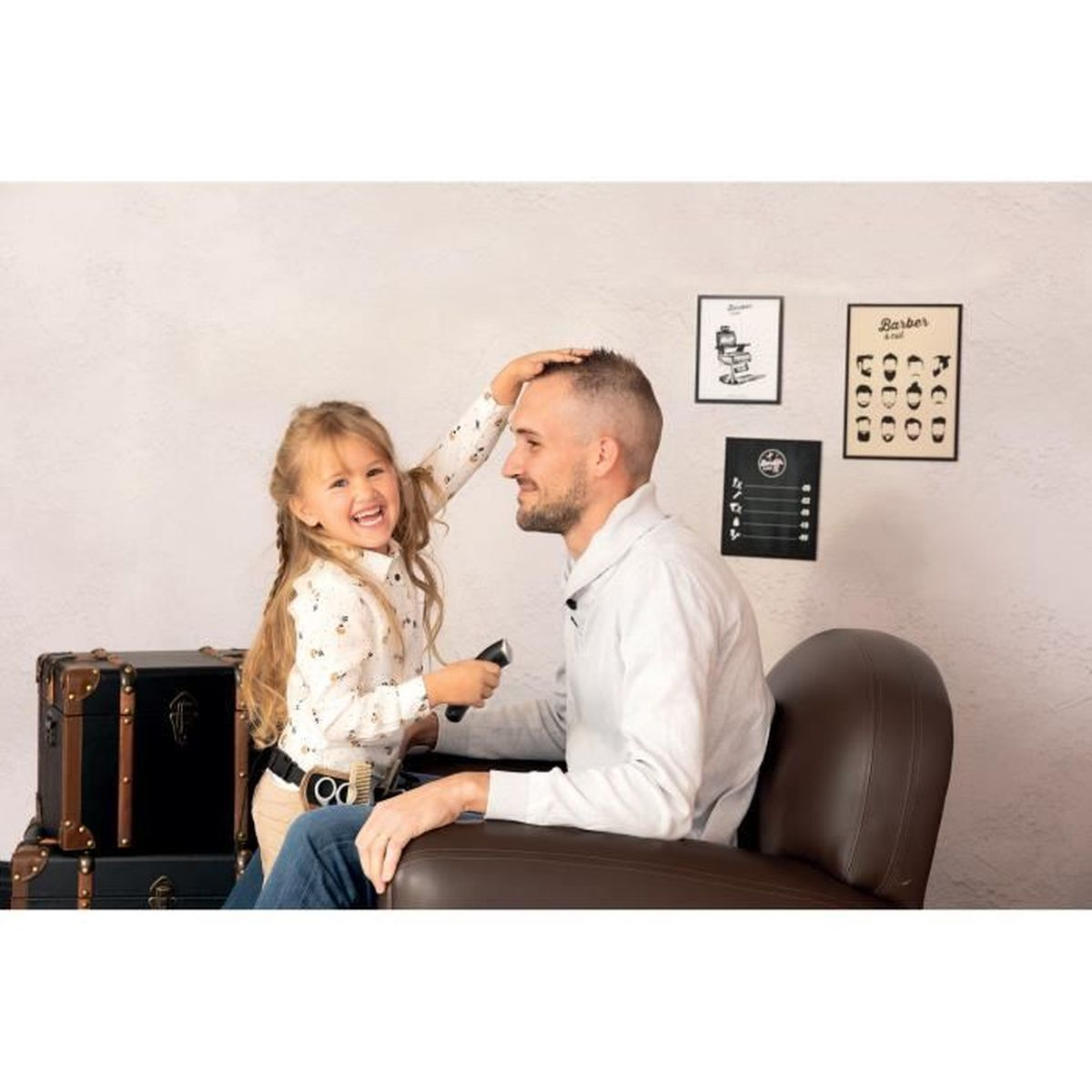 Ein kleines Mädchen schert mit einer Schere das Haar eines Mannes in einem Friseursalon.