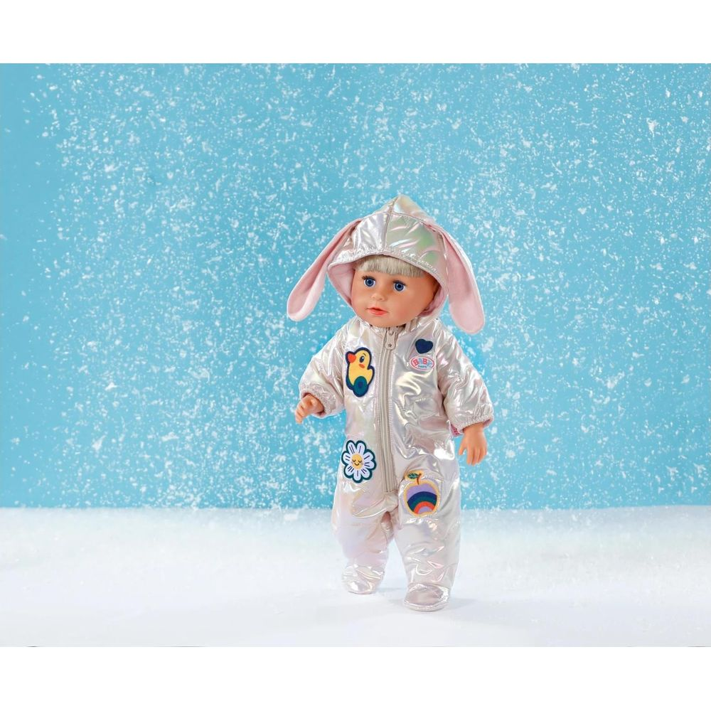 Lalka Baby Born w błyszczącym kombinezonie z króliczymi uszami, na śniegu.
