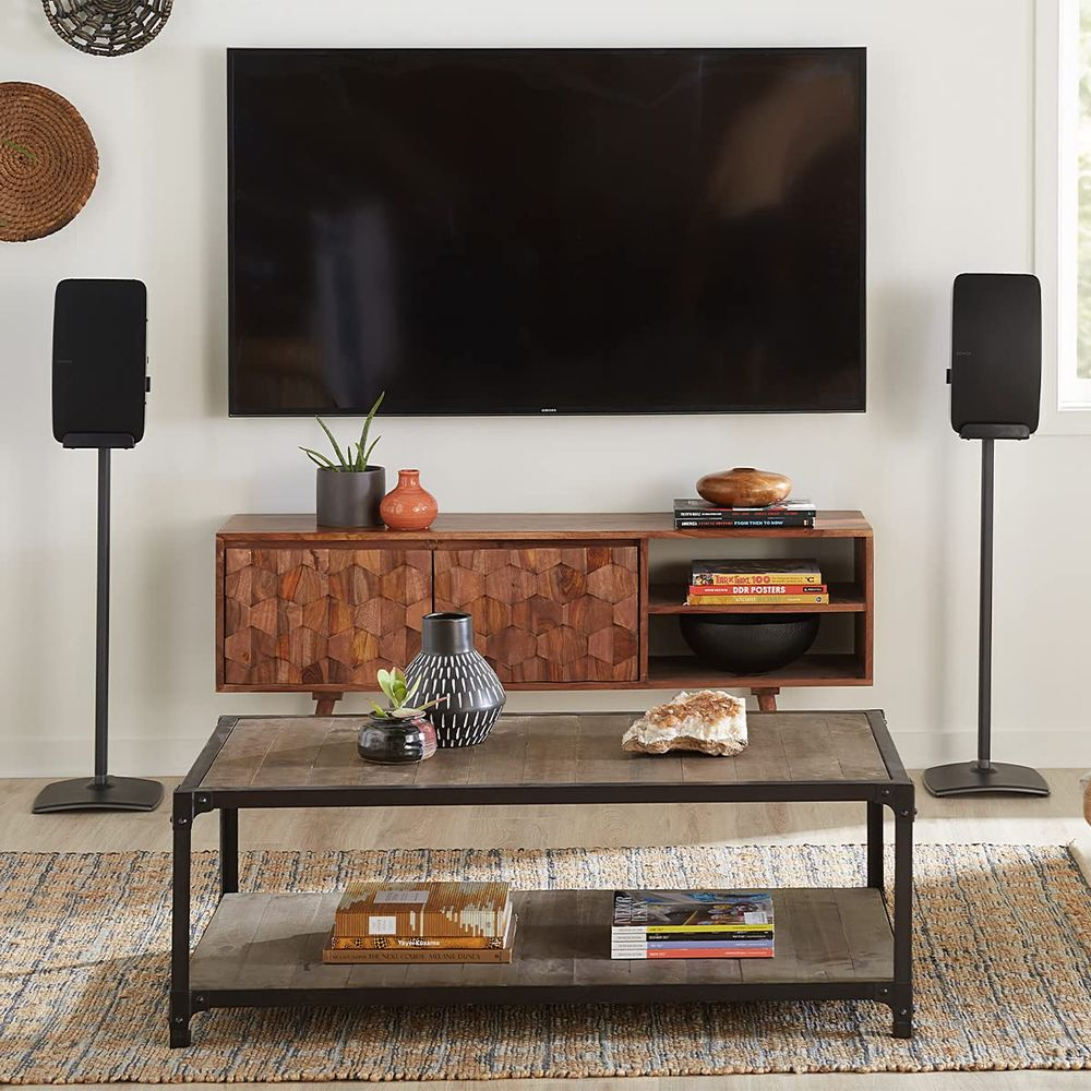 Ein Wohnzimmer mit einem Fernseher, zwei Lautsprechern, einem Schrank, einem Couchtisch und einem Teppich.