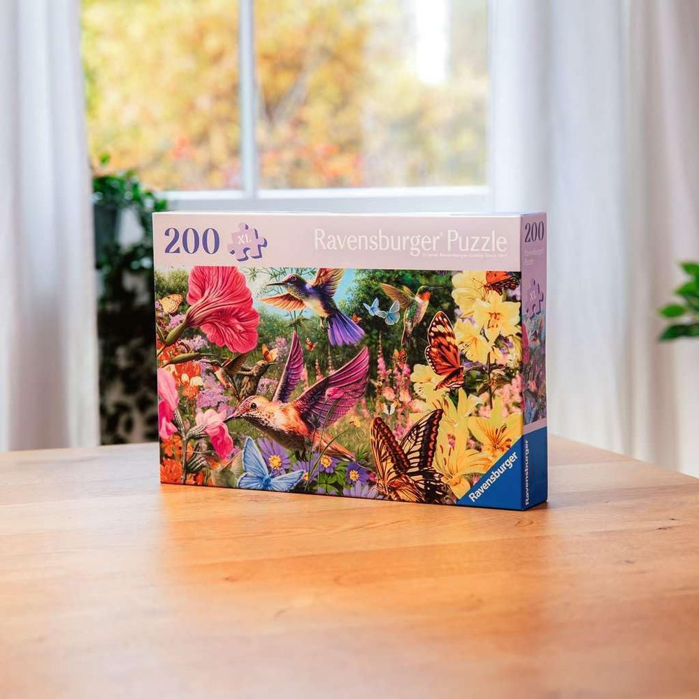 Scatola di puzzle Ravensburger con colibrì e farfalle tra i fiori.