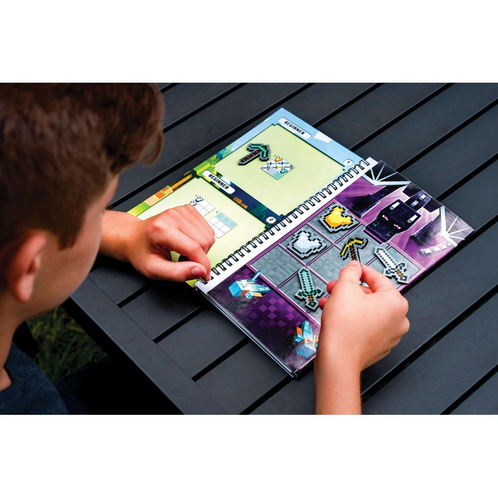 Un enfant place des autocollants pixel art sur un livre sur le thème de Minecraft.
