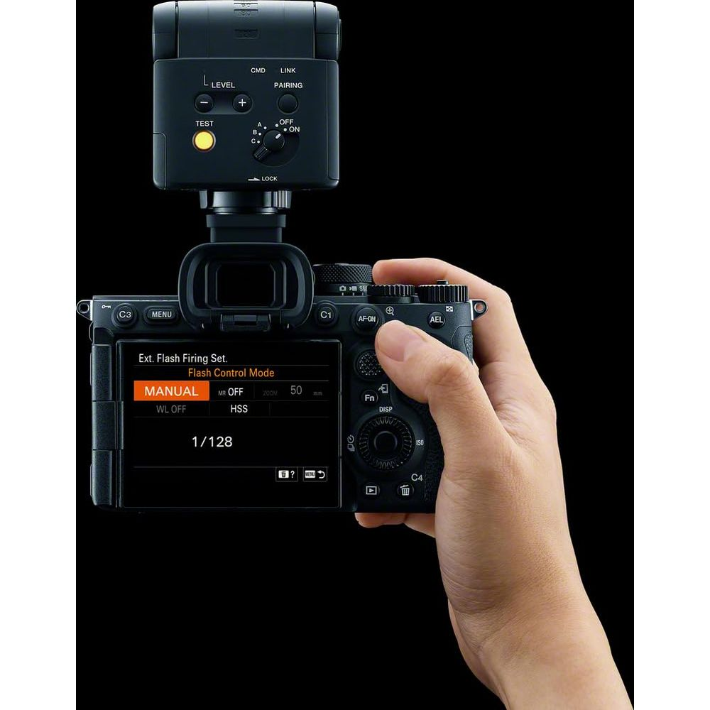 Mano tiene fotocamera con flash esterno. Schermo mostra impostazioni flash, potenza 1/128.