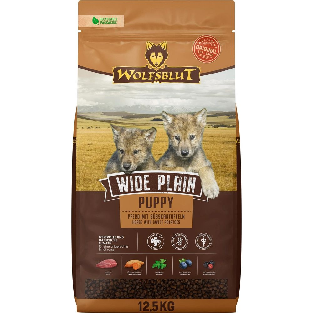 Torba karmy dla psów z dwoma szczeniętami wilka na pierwszym planie, krajobraz łąki w tle.