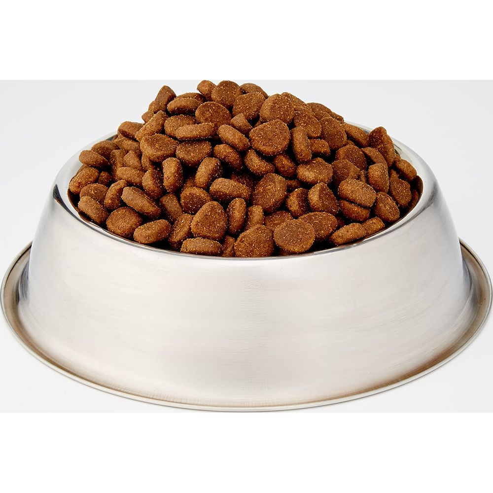 Srebrna miska wypełniona brązową karmą na białym tle.