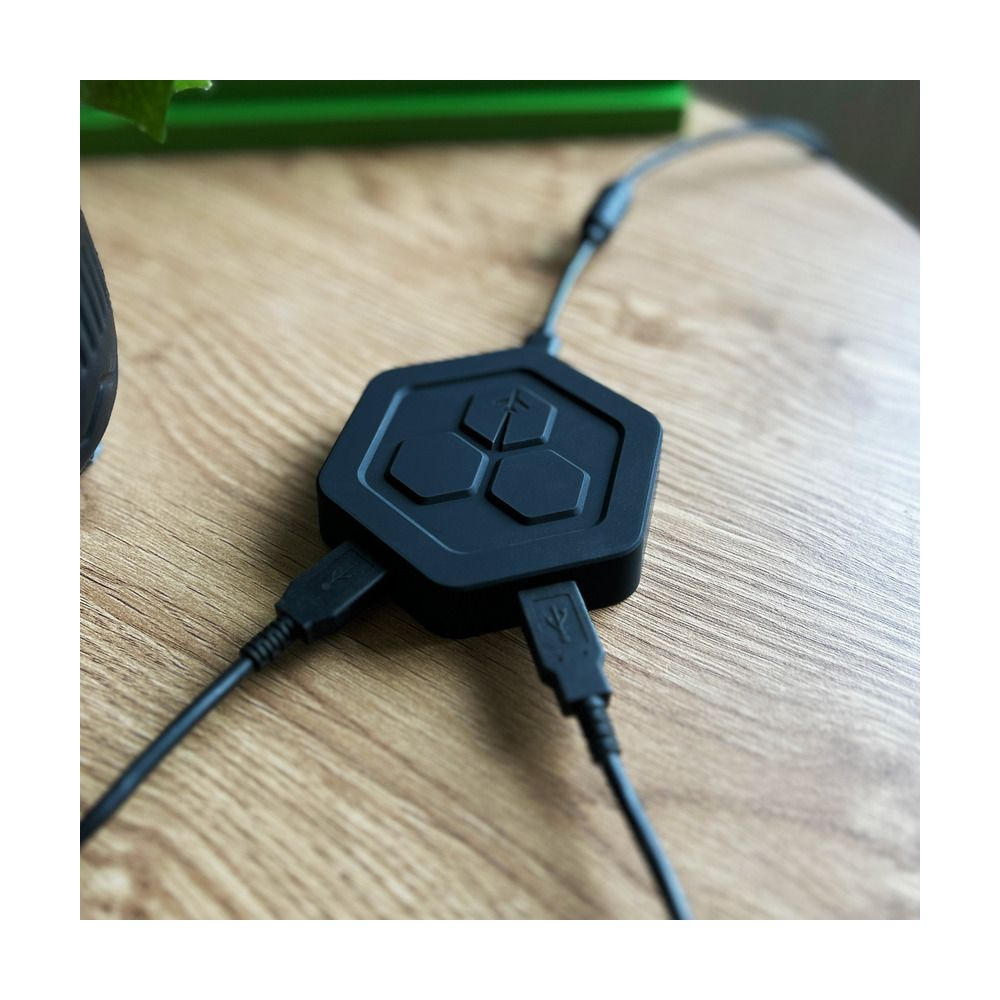 Schwarzer hexagonaler USB-Hub mit drei angeschlossenen Kabeln auf Holztisch.