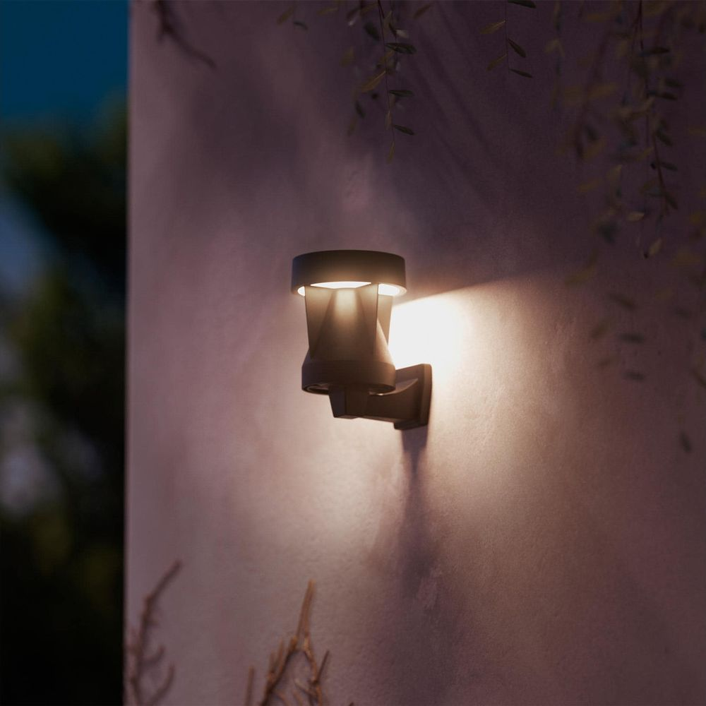 Eine dunkle Wandleuchte mit warmem Licht leuchtet an einer Wand.
